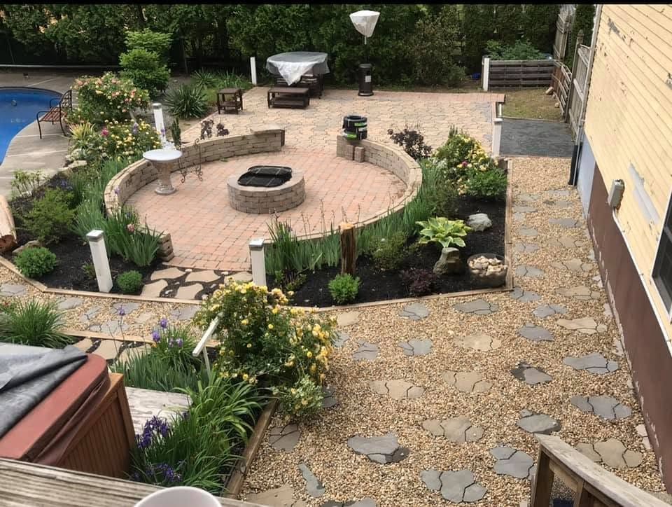 Circular paver terrace with a curved seat wall and stone fire pit, linked to the pool by a flagstone-in-pea-stone path