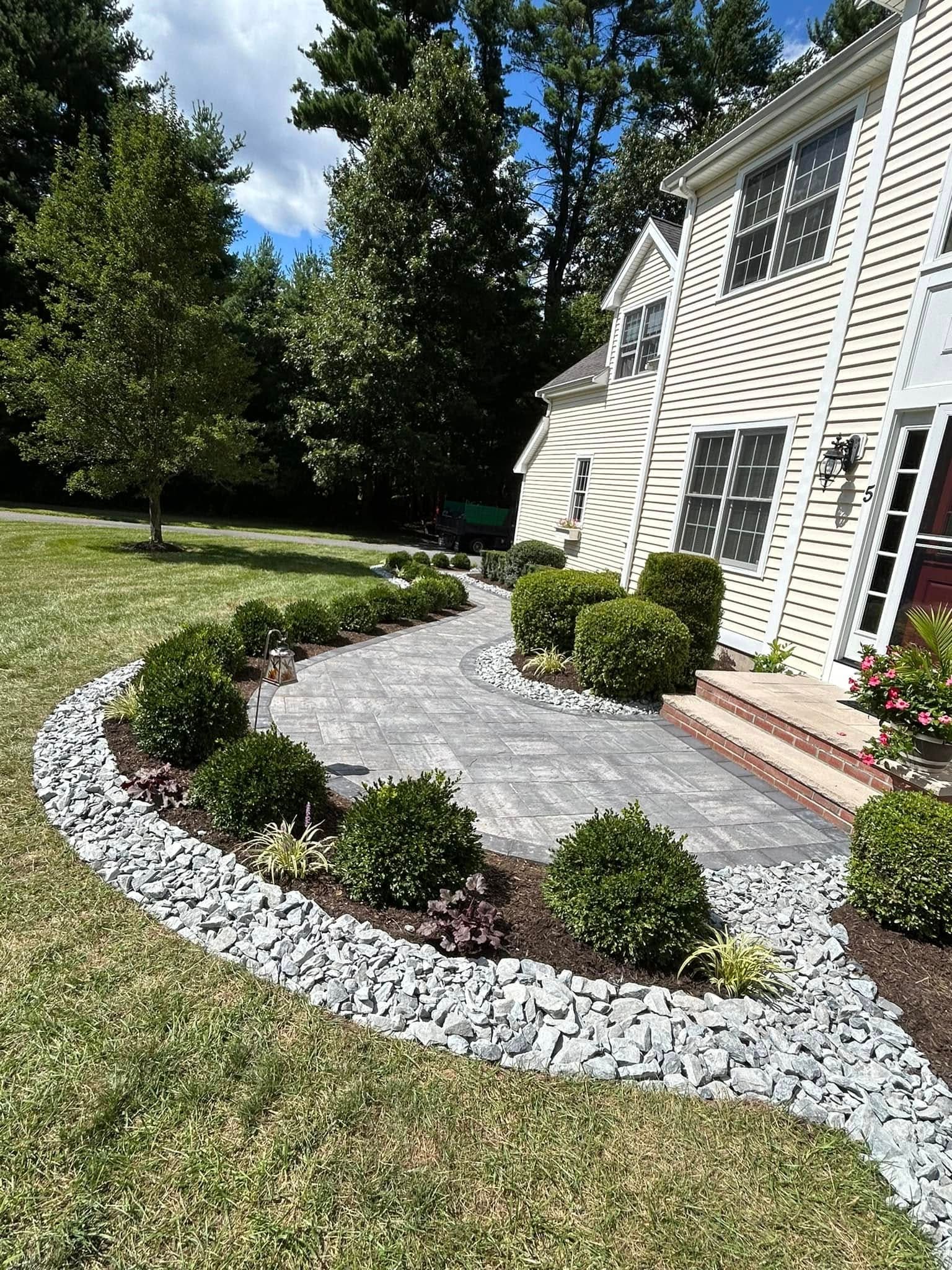 Curved paver walkway sweeping from the lawn to a colonial front entry, edged in boxwood and white stone