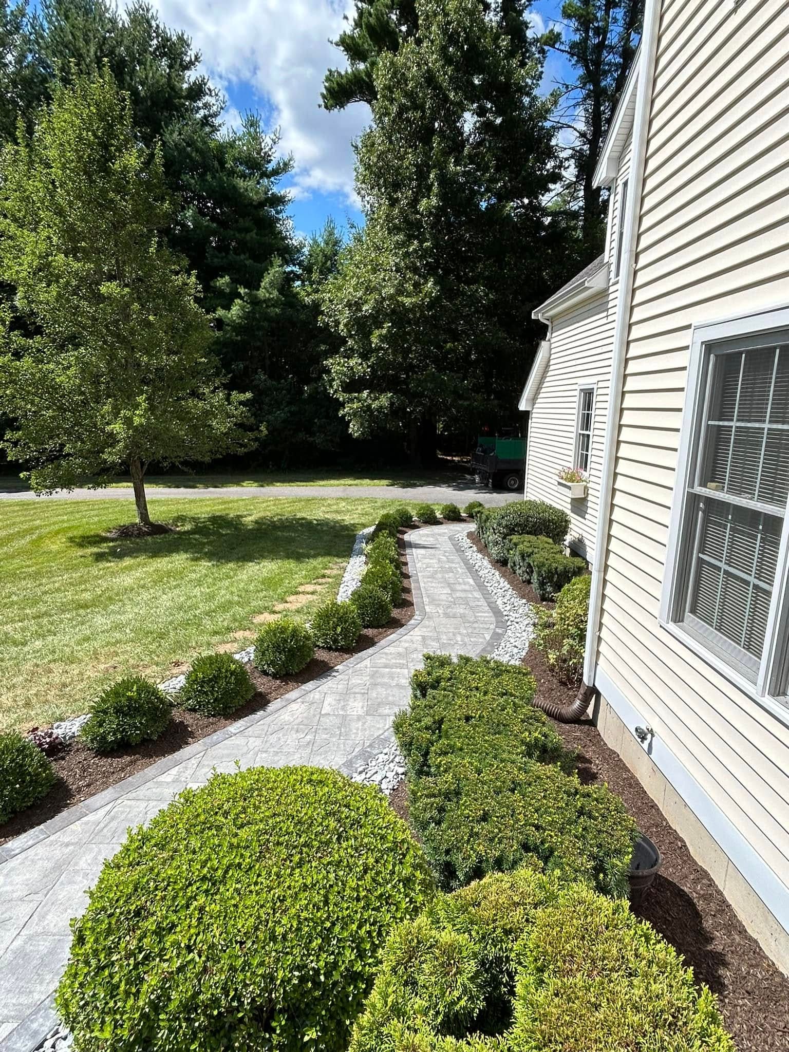 Paver walk with a soldier-course border curving past foundation planting toward the street